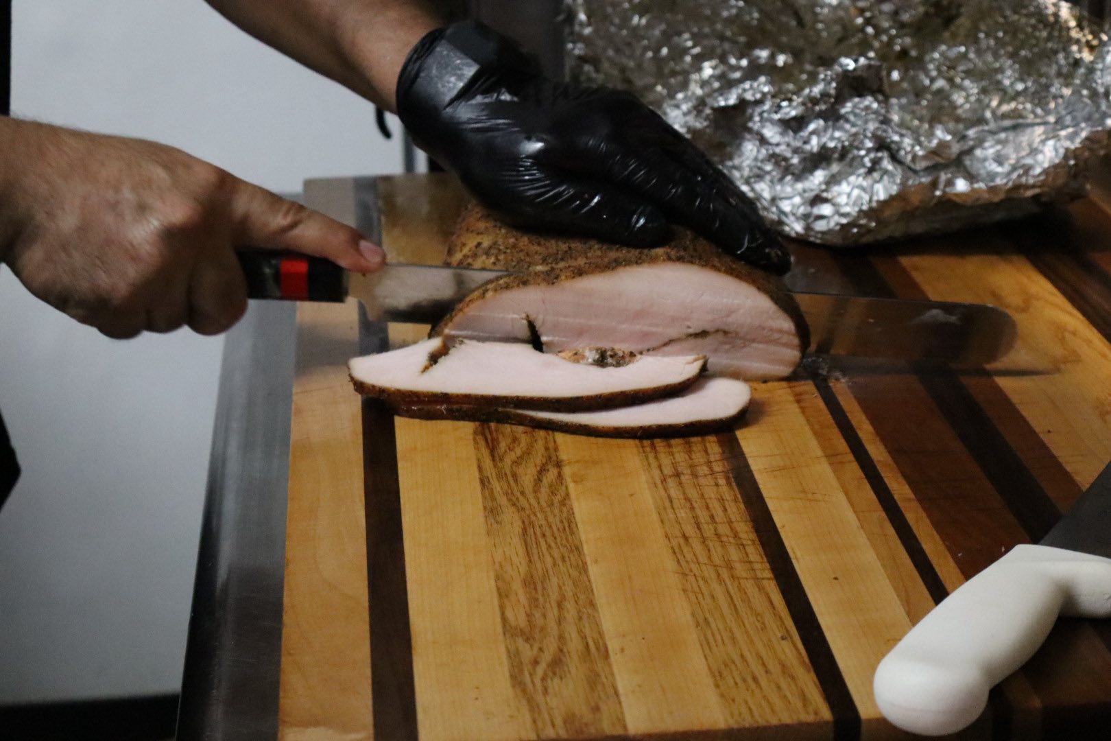 Pitmaster slicing fresh smoked turkey breast